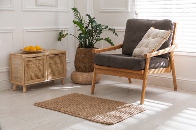 Photo of Stylish rug on floor near armchair in room