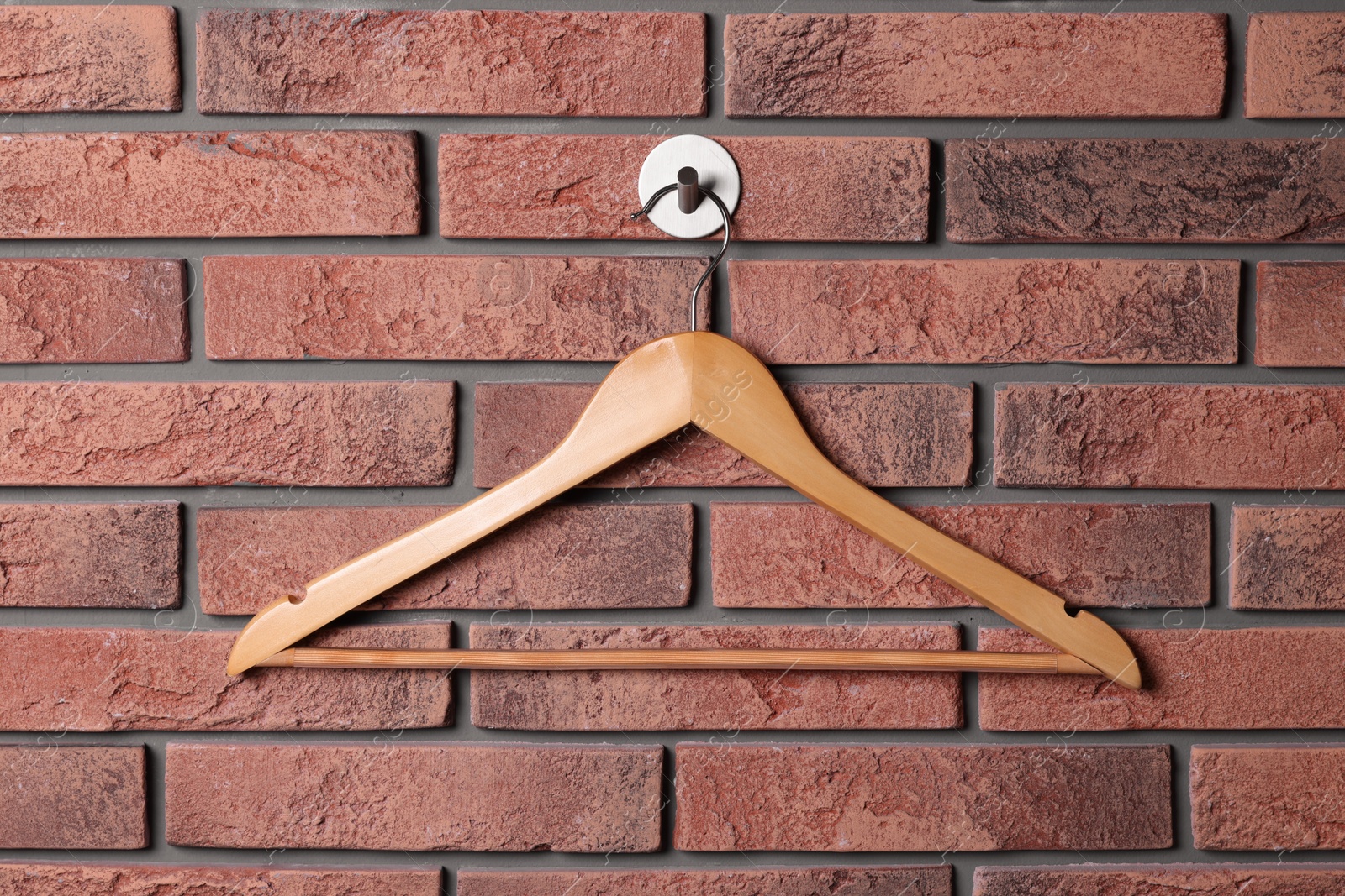 Photo of Wooden clothes hanger on red brick wall