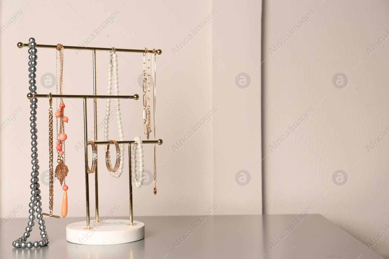 Photo of Holder with set of luxurious jewelry on grey table. Space for text