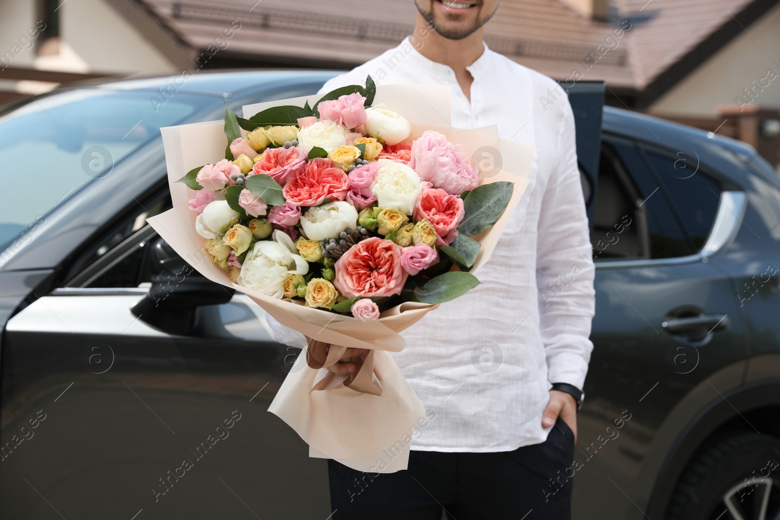 Photo of Young man with beautiful flower bouquet near car outdoors, closeup view