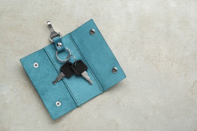 Photo of Stylish leather holder with keys on light grey table, top view. Space for text