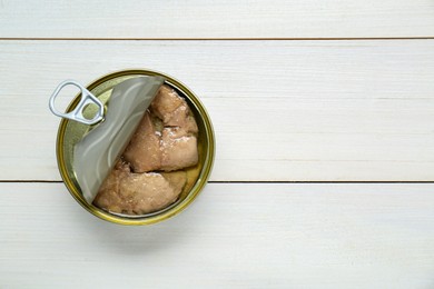 Open tin can of tasty cod liver on white wooden table, top view. Space for text