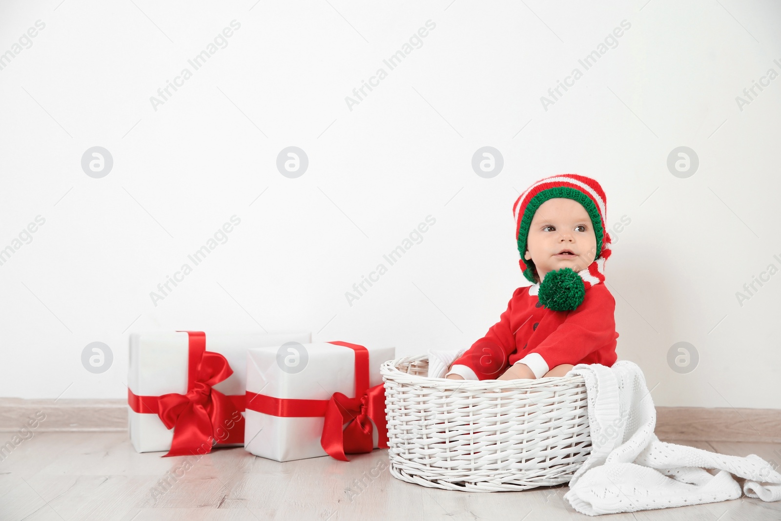 Photo of Cute little baby wearing Christmas costume in basket at home