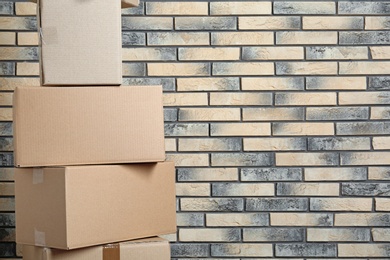 Stack of cardboard boxes near brick wall. Space for text