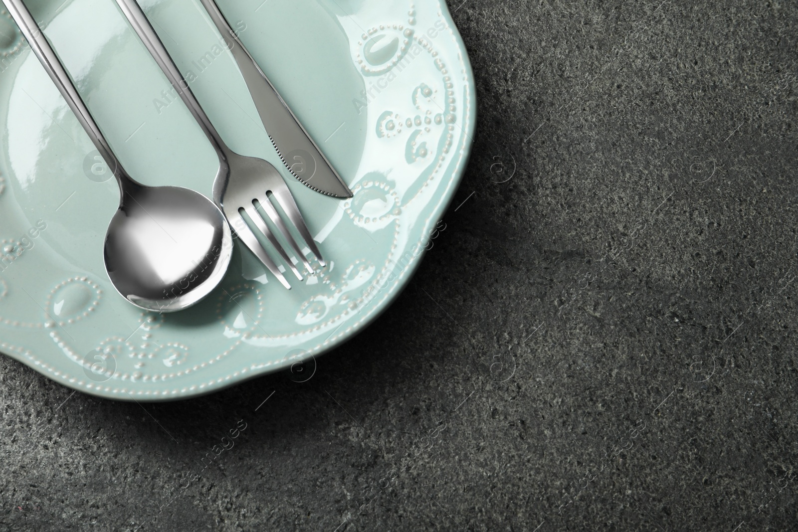 Photo of Stylish silver cutlery and plate on grey table, top view. Space for text