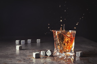 Photo of Glass with liquor splash and whiskey stones on table