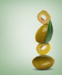 Image of Cut and whole olives with leaf on pastel green background, space for text