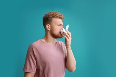 Photo of Young man suffering from allergy on blue background