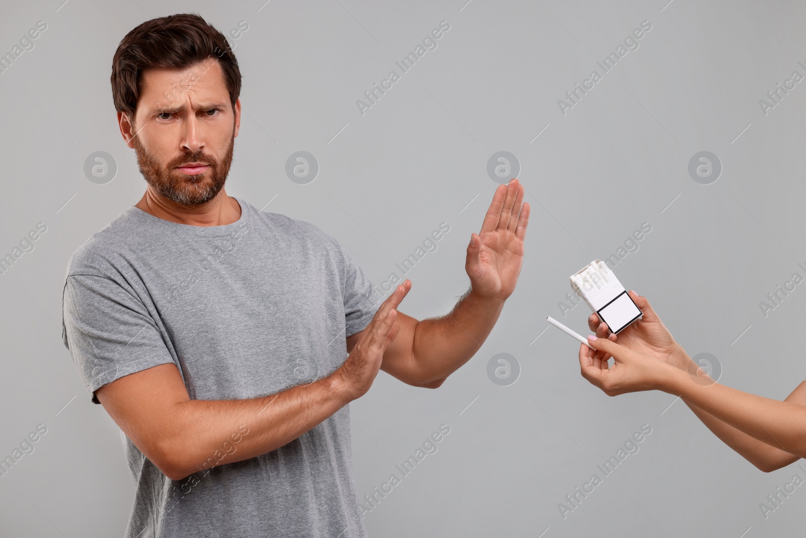 Photo of Stop smoking concept. Man refusing cigarettes on grey background