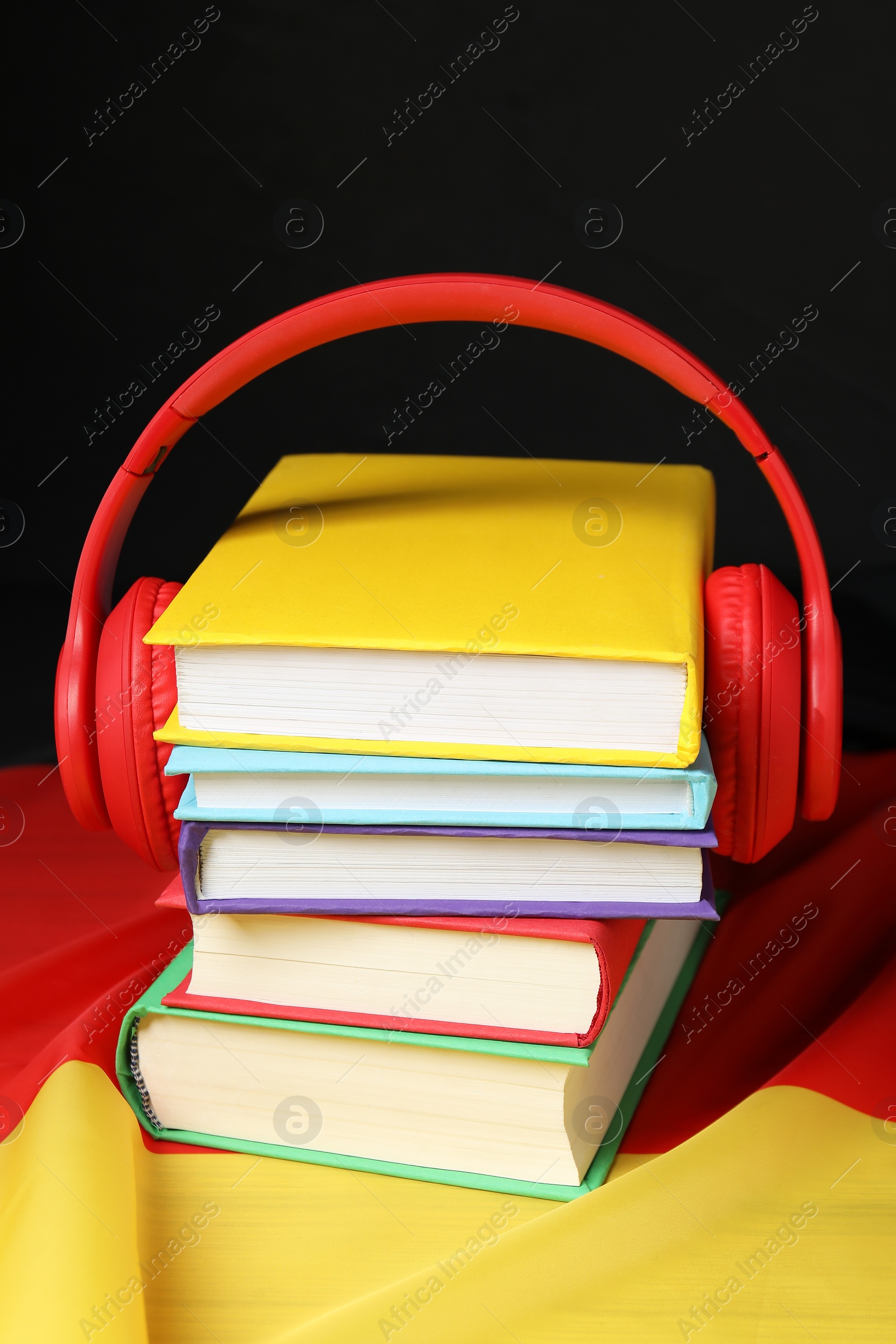 Photo of Learning foreign language. Different books and headphones on flag of Germany