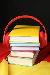 Photo of Learning foreign language. Different books and headphones on flag of Germany