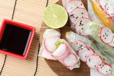 Delicious spring rolls, lime and soy sauce on table, top view