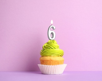 Photo of Birthday cupcake with number six candle on violet background