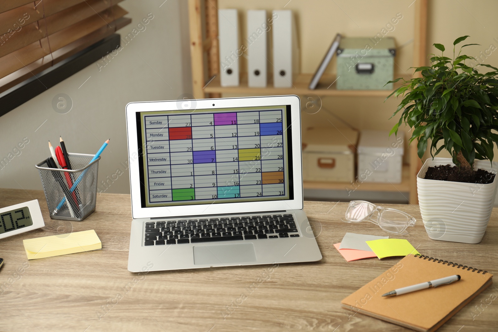 Photo of Modern laptop with calendar app at table in office