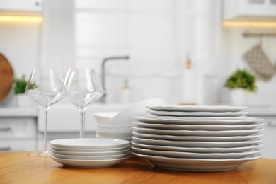 Clean plates, bowls and glasses on wooden table in kitchen