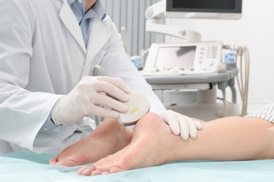 Photo of Doctor conducting ultrasound examination of patient's foot in clinic, closeup