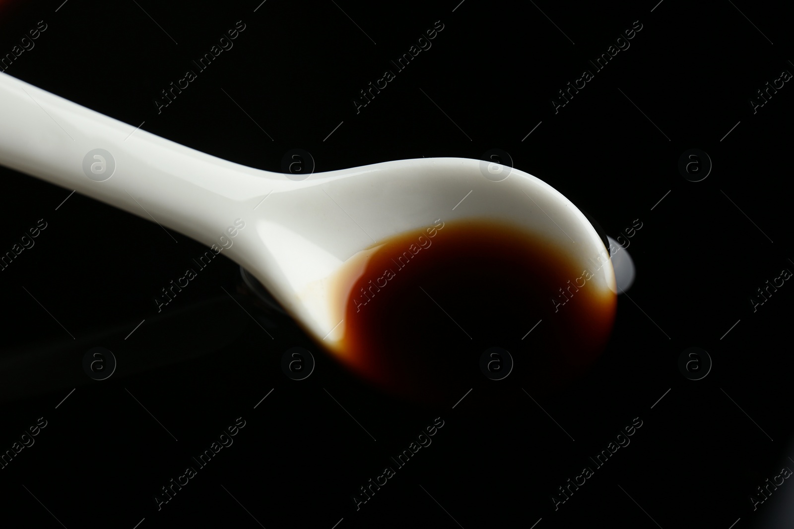 Photo of Ceramic spoon and soy sauce as background, closeup