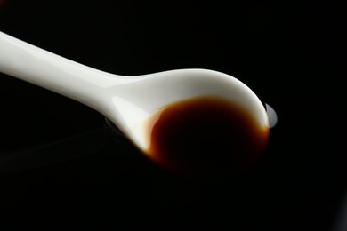 Ceramic spoon and soy sauce as background, closeup