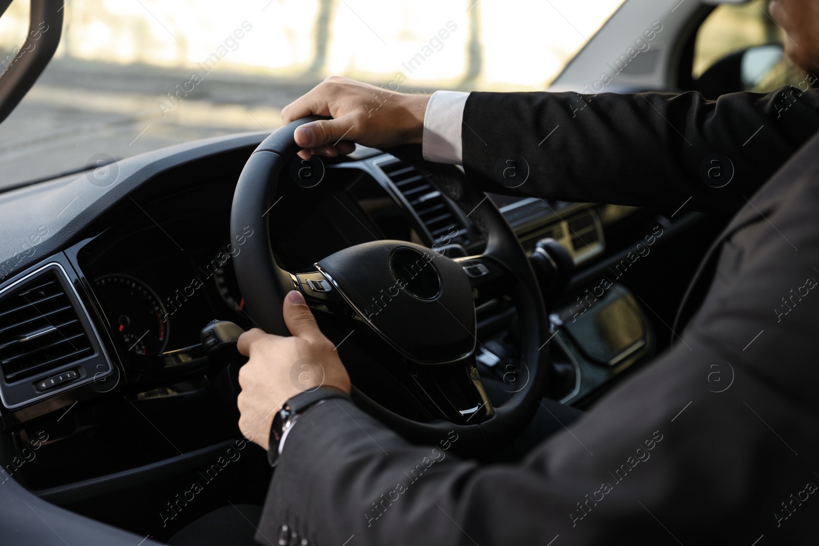 Photo of Professional driver in luxury car, closeup. Chauffeur service