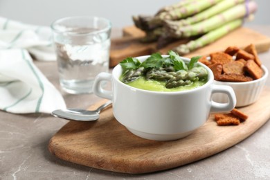 Photo of Delicious asparagus soup served on grey marble table