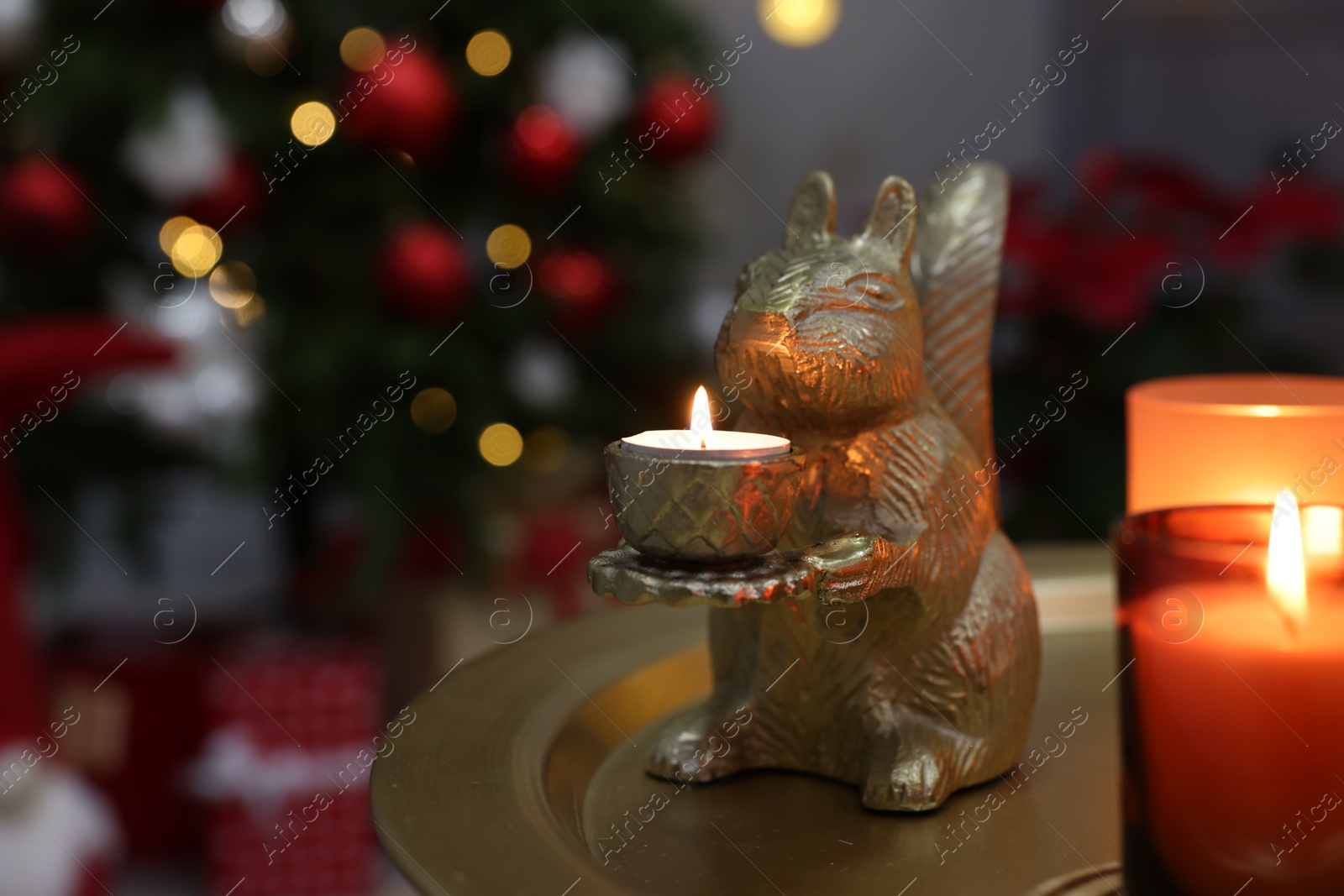 Photo of Cute squirrel shaped candle holder on table in room decorated for Christmas, space for text