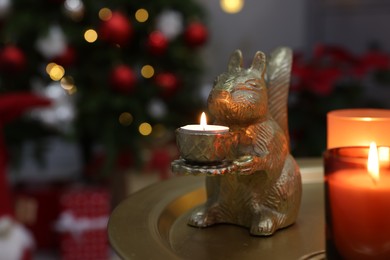 Photo of Cute squirrel shaped candle holder on table in room decorated for Christmas, space for text