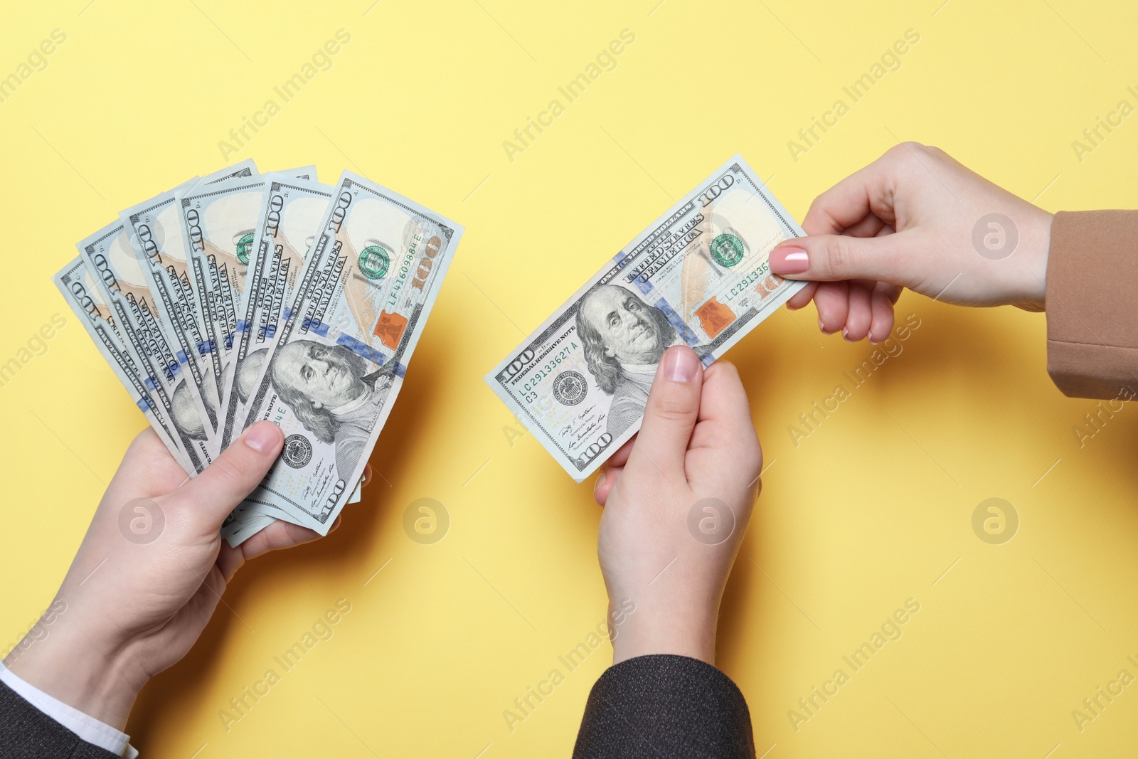 Photo of Man giving money to woman on yellow background, closeup. Currency exchange