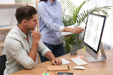 Image of Colleagues working with technical drawing on computer in office