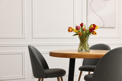 Photo of Vase with beautiful tulips on table in dining room