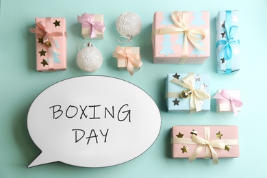 Speech bubble with phrase BOXING DAY and Christmas decorations on light blue background, flat lay