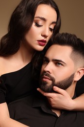 Photo of Handsome bearded man with sexy lady on brown background, closeup