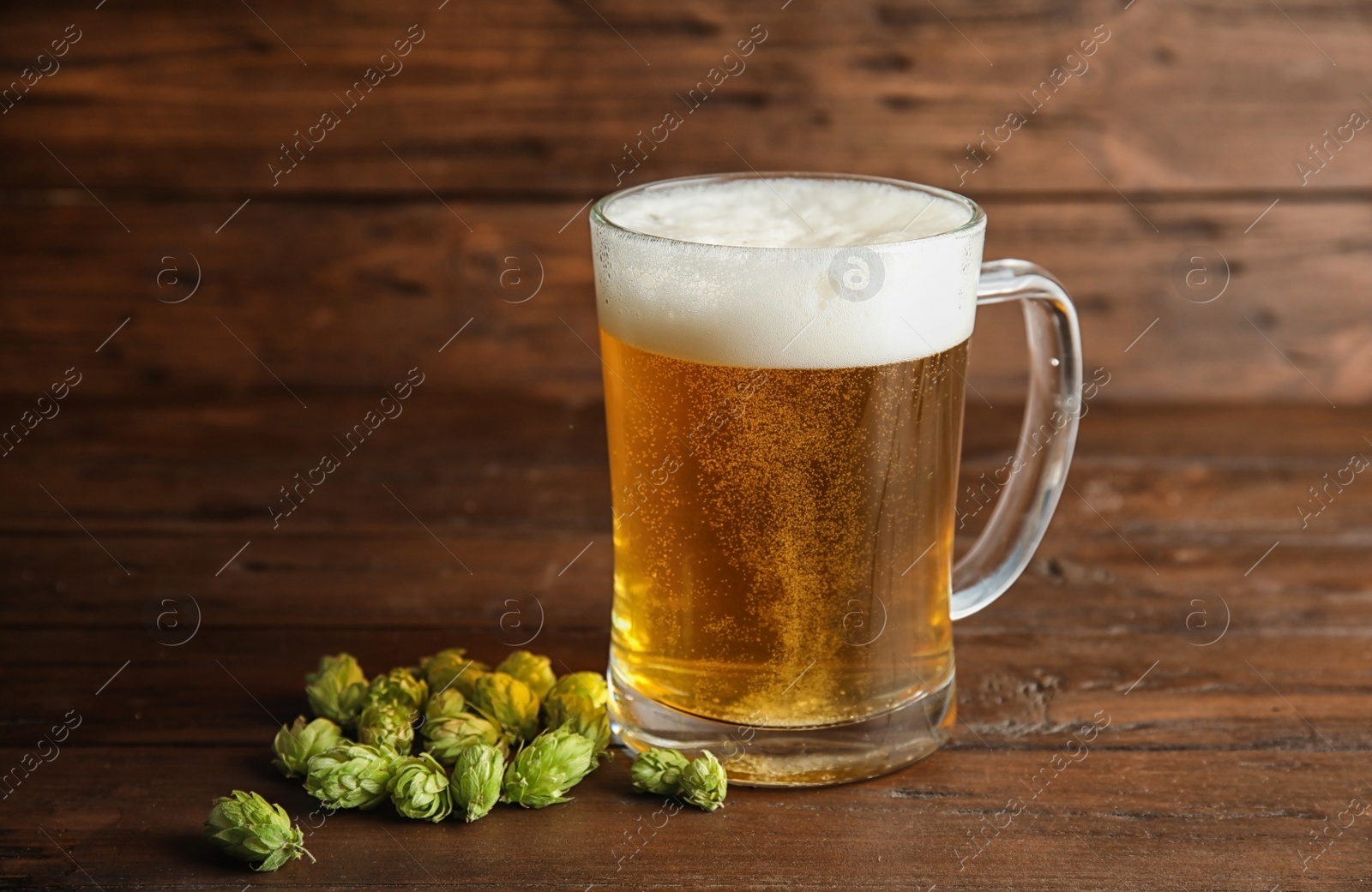 Photo of Composition with tasty beer and fresh green hops on wooden table