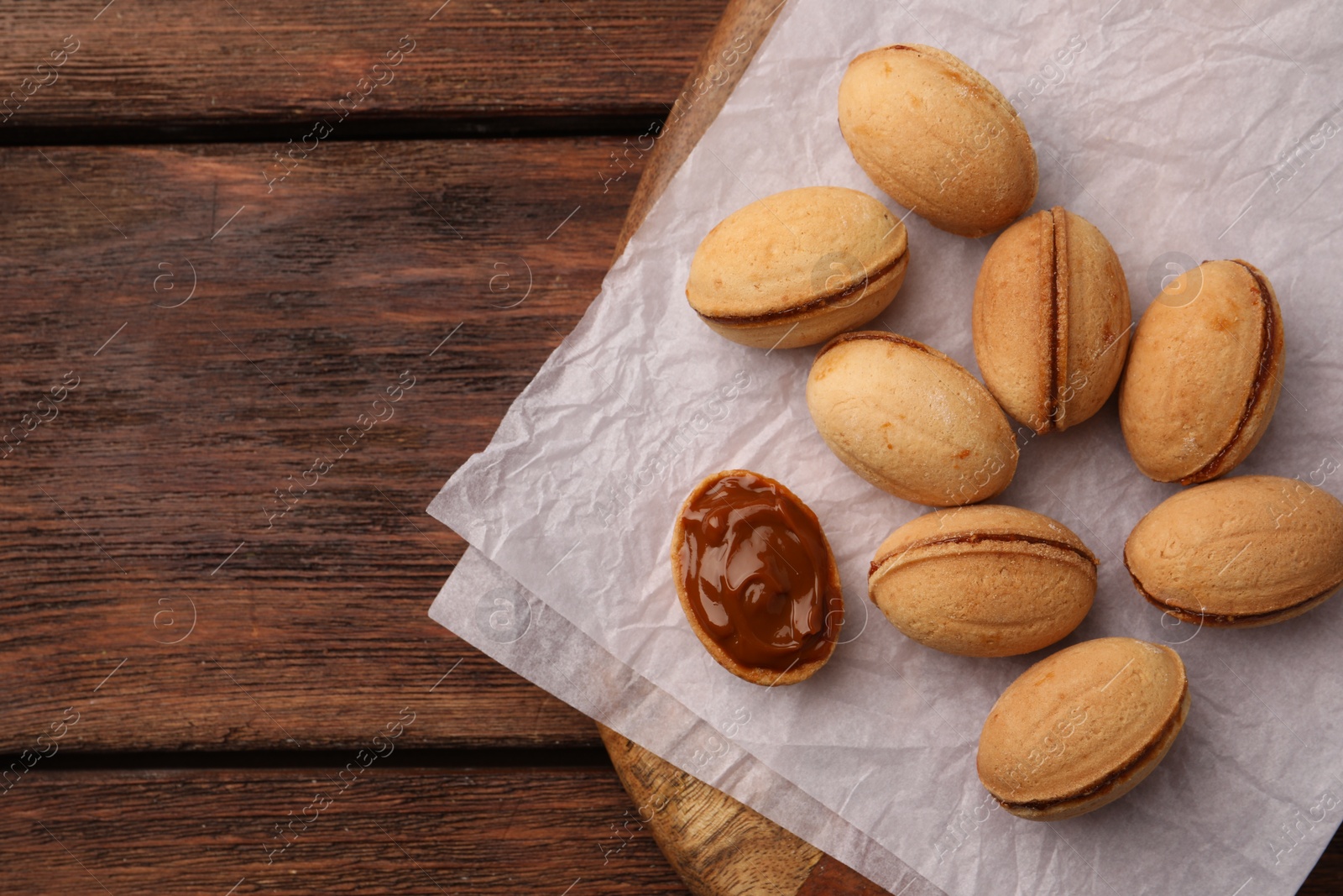 Delicious nut shaped cookies with boiled condensed milk on wooden table, flat lay. Space for text Photo of Delicious nut shaped cookies with boiled condensed milk on wooden table, flat lay. Space for text