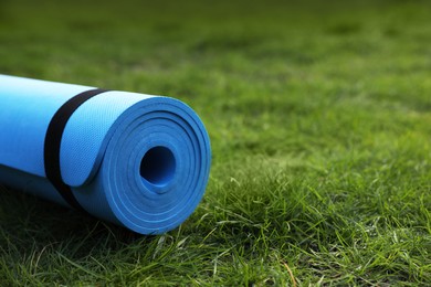 Photo of Bright karemat or fitness mat on fresh green grass outdoors, space for text