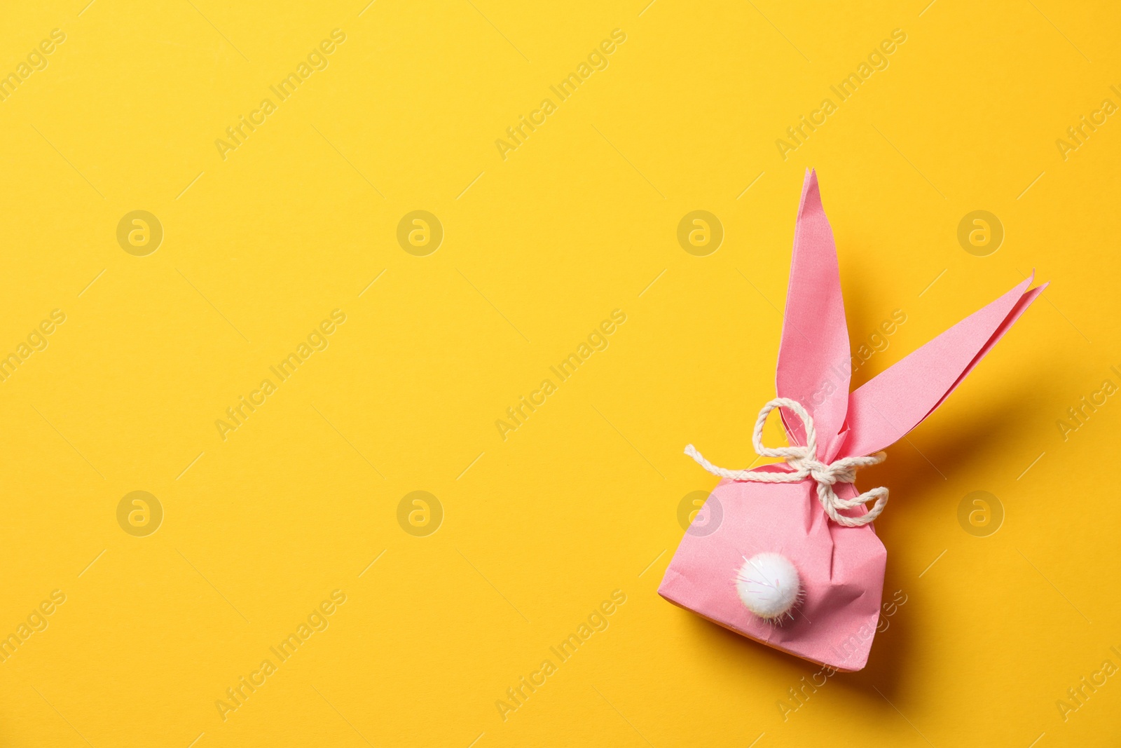 Photo of Creative Easter bunny gift bag on color background, top view with space for text