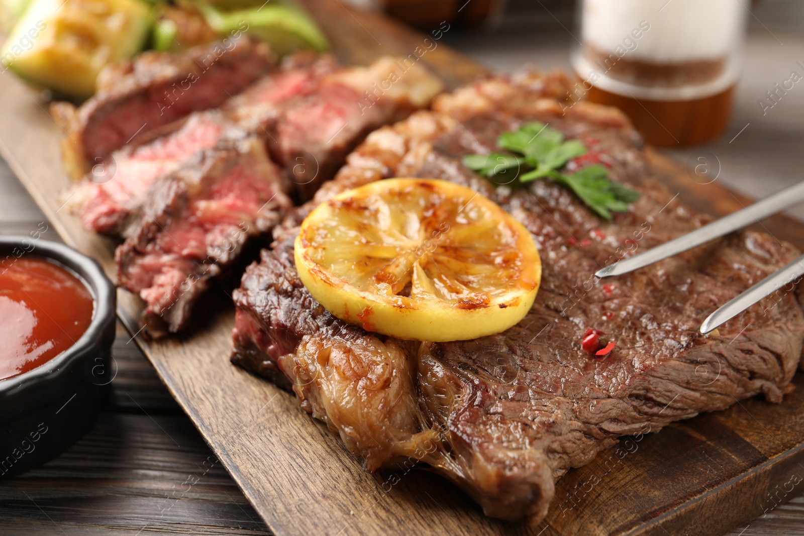 Photo of Delicious grilled beef steak on wooden table, closeup