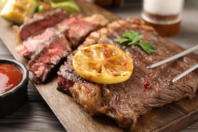 Photo of Delicious grilled beef steak on wooden table, closeup