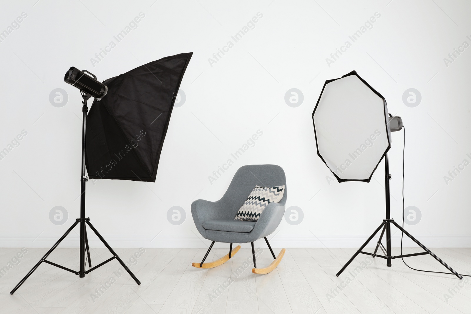Photo of Comfortable rocking chair and professional lighting equipment in photo studio
