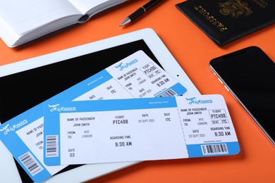 Photo of Composition with avia tickets and tablet on orange background. Travel agency concept
