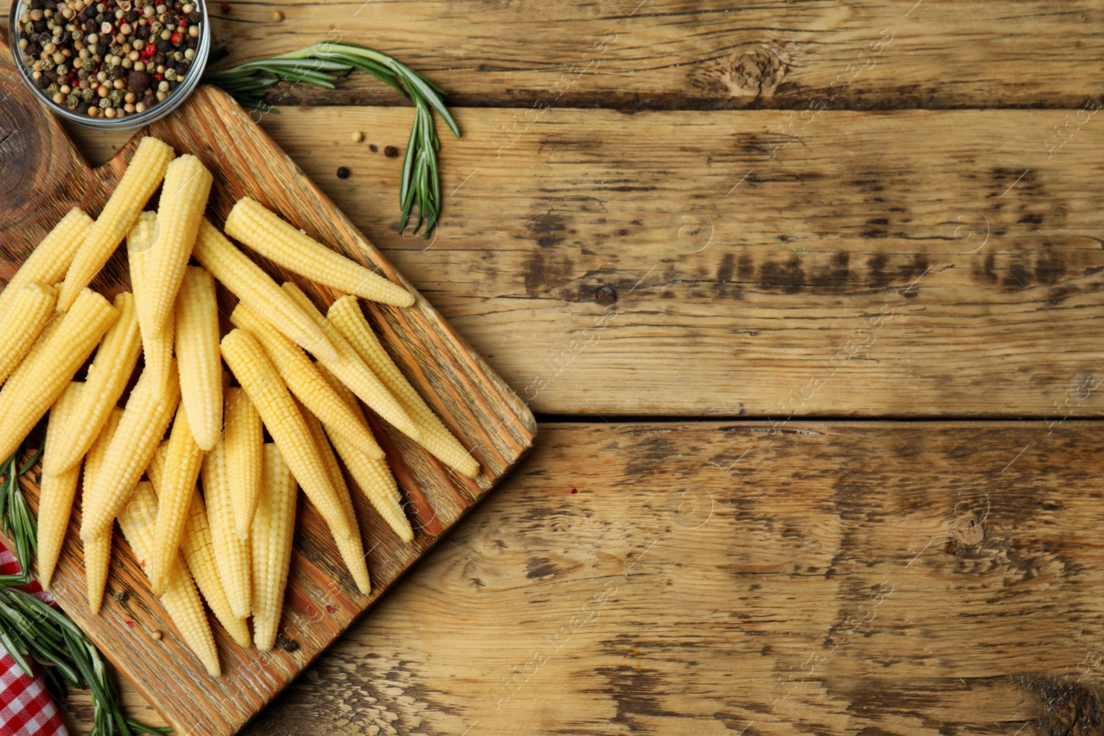 Photo of Fresh baby corn cobs and spices on wooden table, flat lay. Space for text