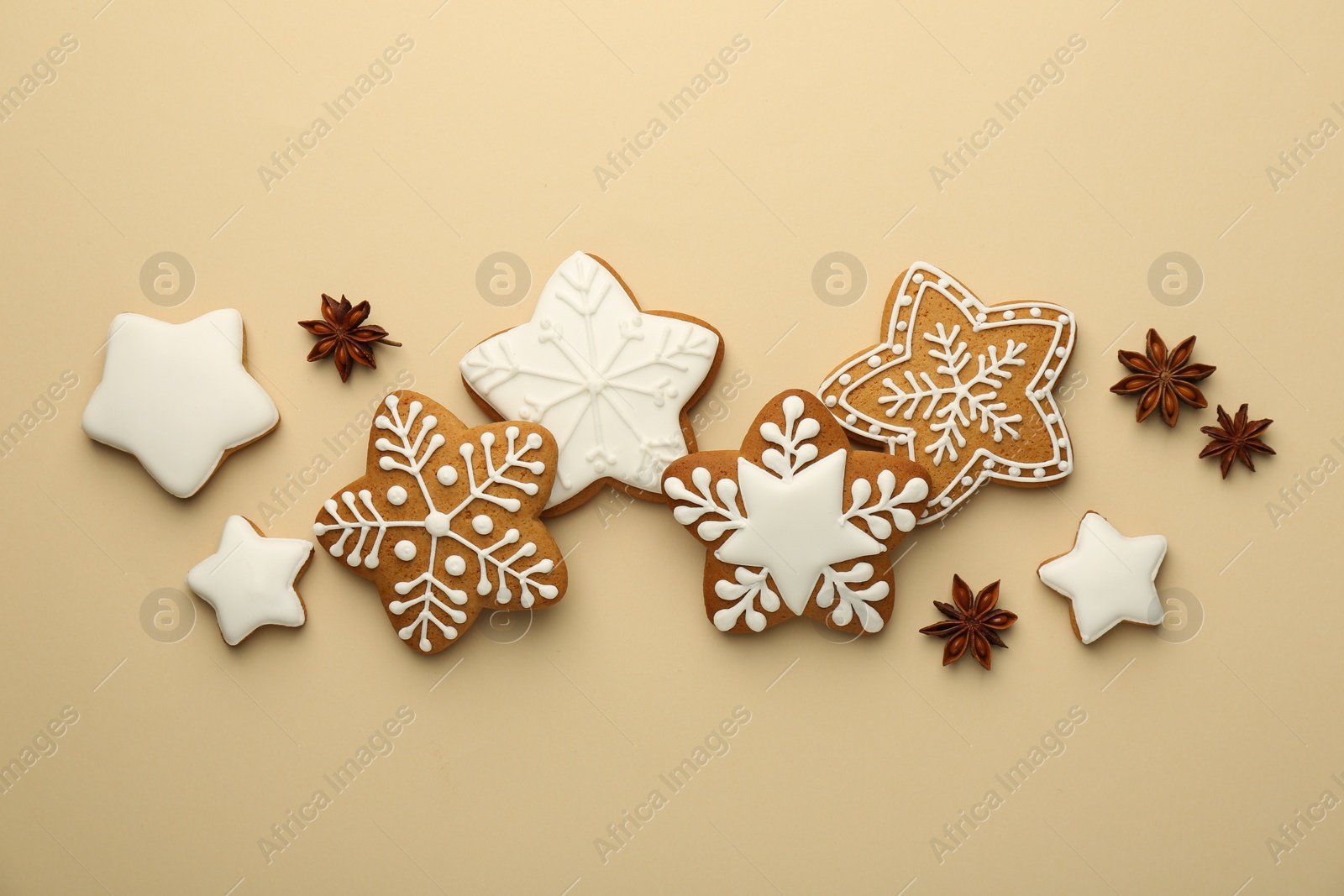 Photo of Tasty Christmas cookies with icing and anise stars on beige background, flat lay