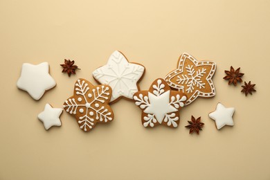 Tasty Christmas cookies with icing and anise stars on beige background, flat lay