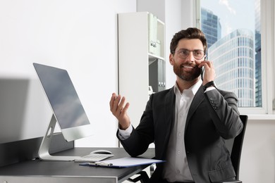 Handsome businessman talking on smartphone at workplace in office