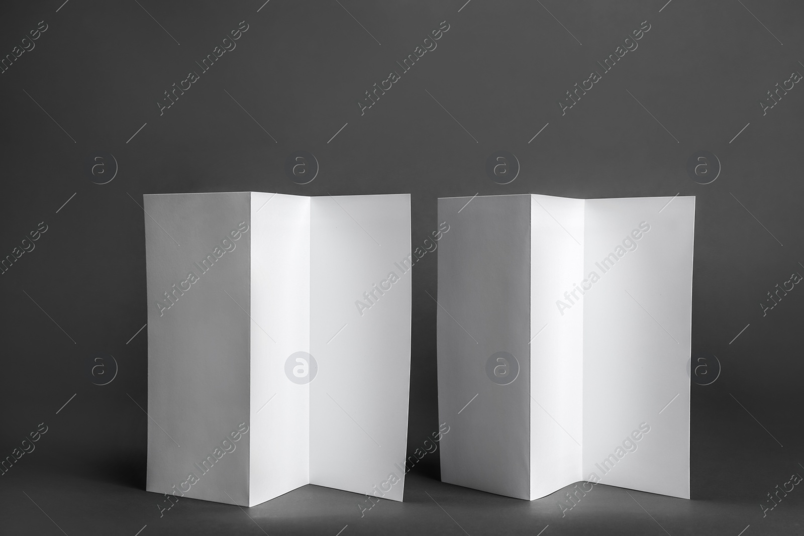 Photo of Two blank brochures on dark grey background. Mock up for design