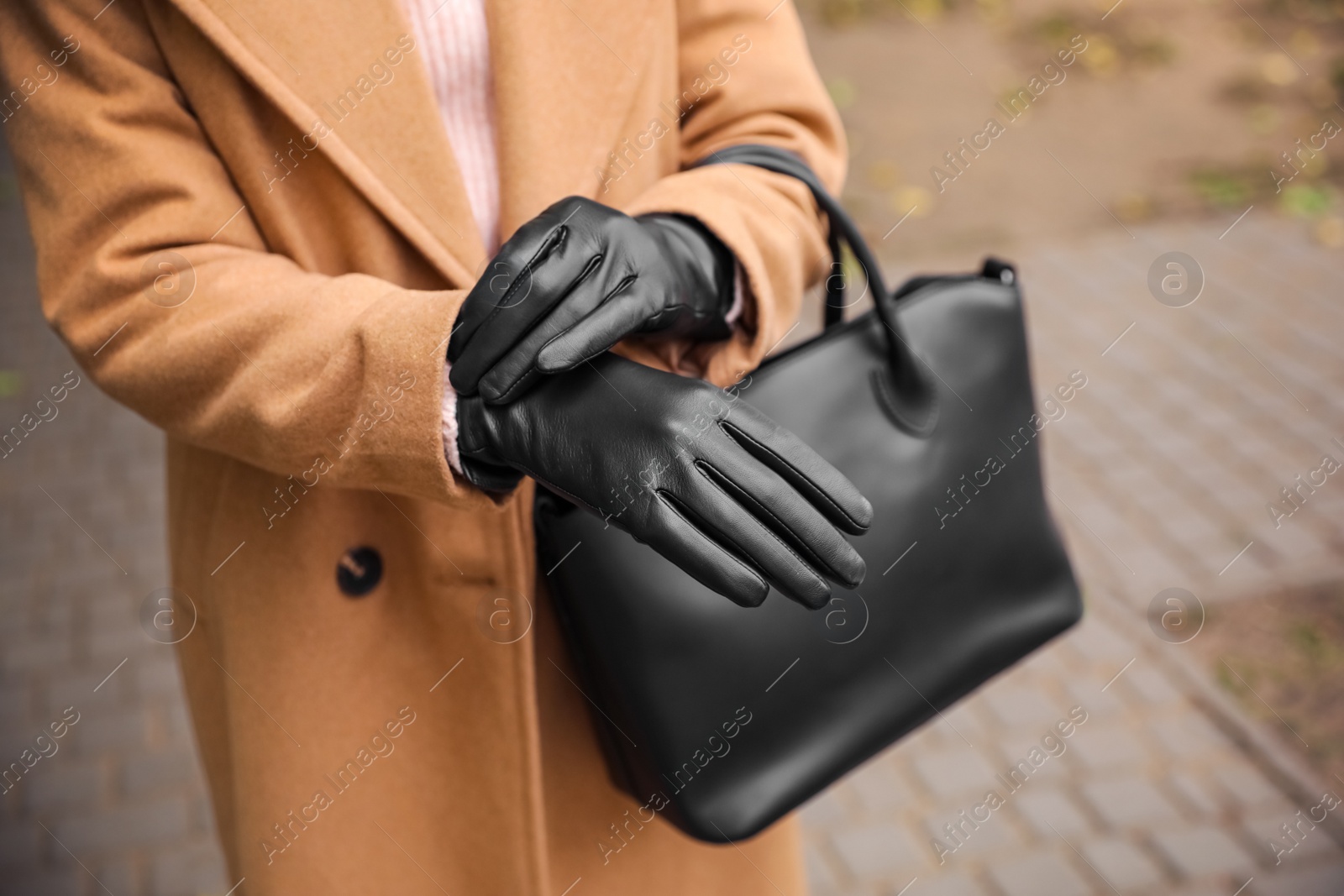 Photo of Young woman in black leather gloves, closeup. Stylish clothes