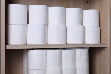 Stacked toilet paper rolls on wooden shelves