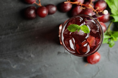 Photo of Delicious grape soda water on black table, flat lay. Refreshing drink