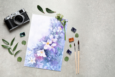 Photo of Flat lay composition with watercolor paints and floral picture on grey stone table