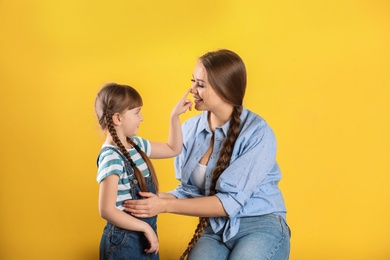 Happy woman and daughter in stylish clothes on color background