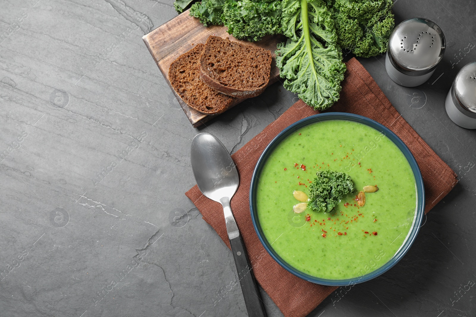 Photo of Tasty kale soup served on grey table, flat lay